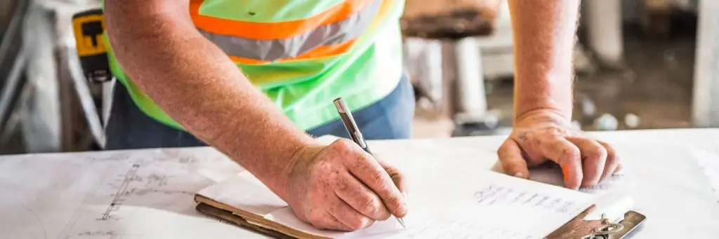 Man in Hi-Vis Writing on Clipboard