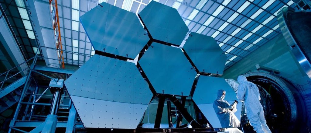Person in Lab Suit in front of Hexagonal Panels