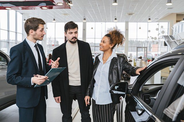 Salesman Showing A Couple A Car in the Showroom