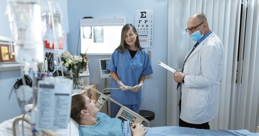 Doctors Speaking to Patient in Hospital Bed